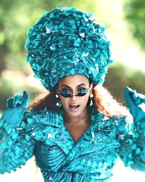 Beyonce in a blue jacket, gloves, and beehive hat in Black Is King.