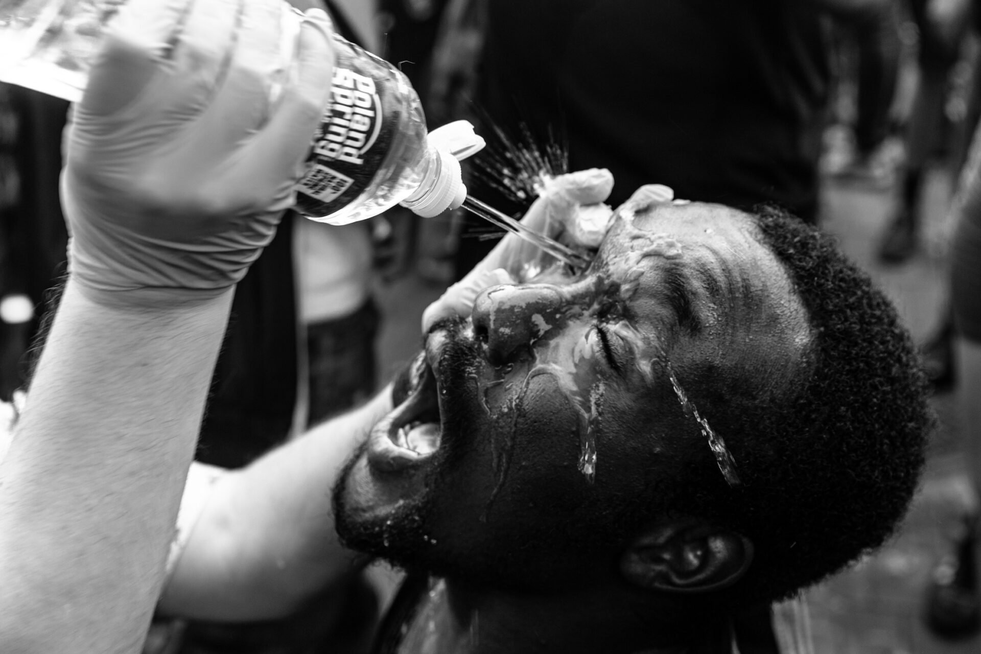 Person drinking water from bottle during outdoor event, black and white photograph